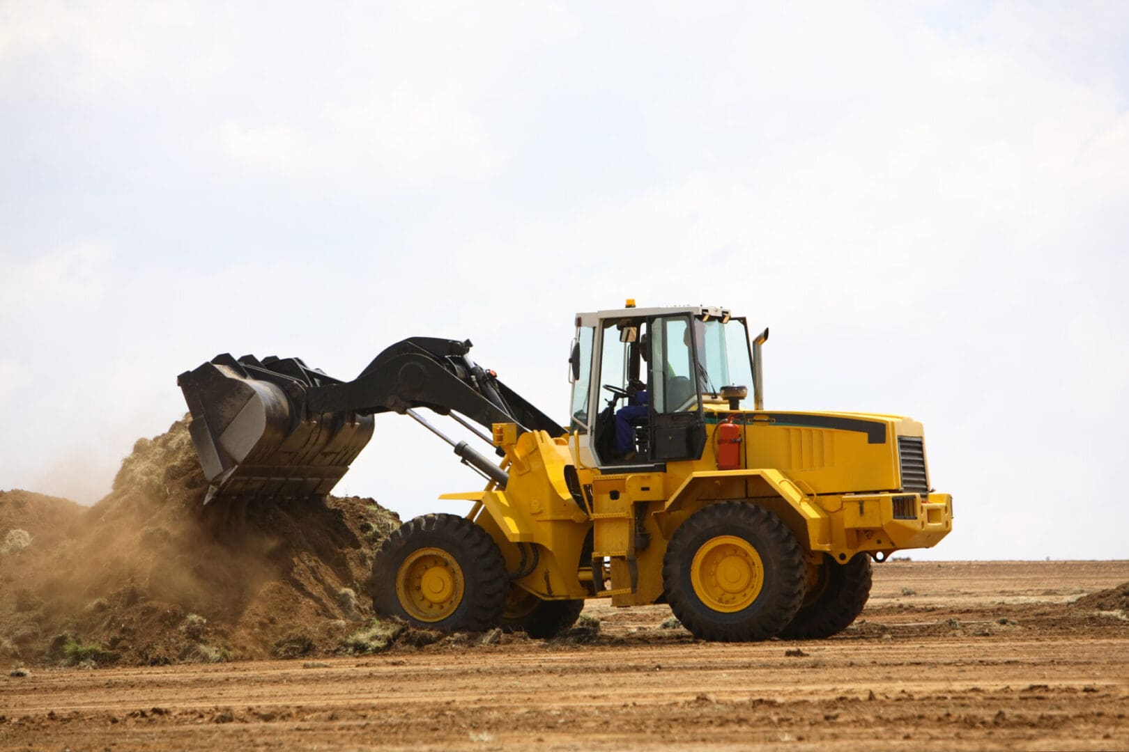 Yellow wheel loader moving dirt.