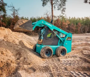 Skid steer loader lifting sand on site.