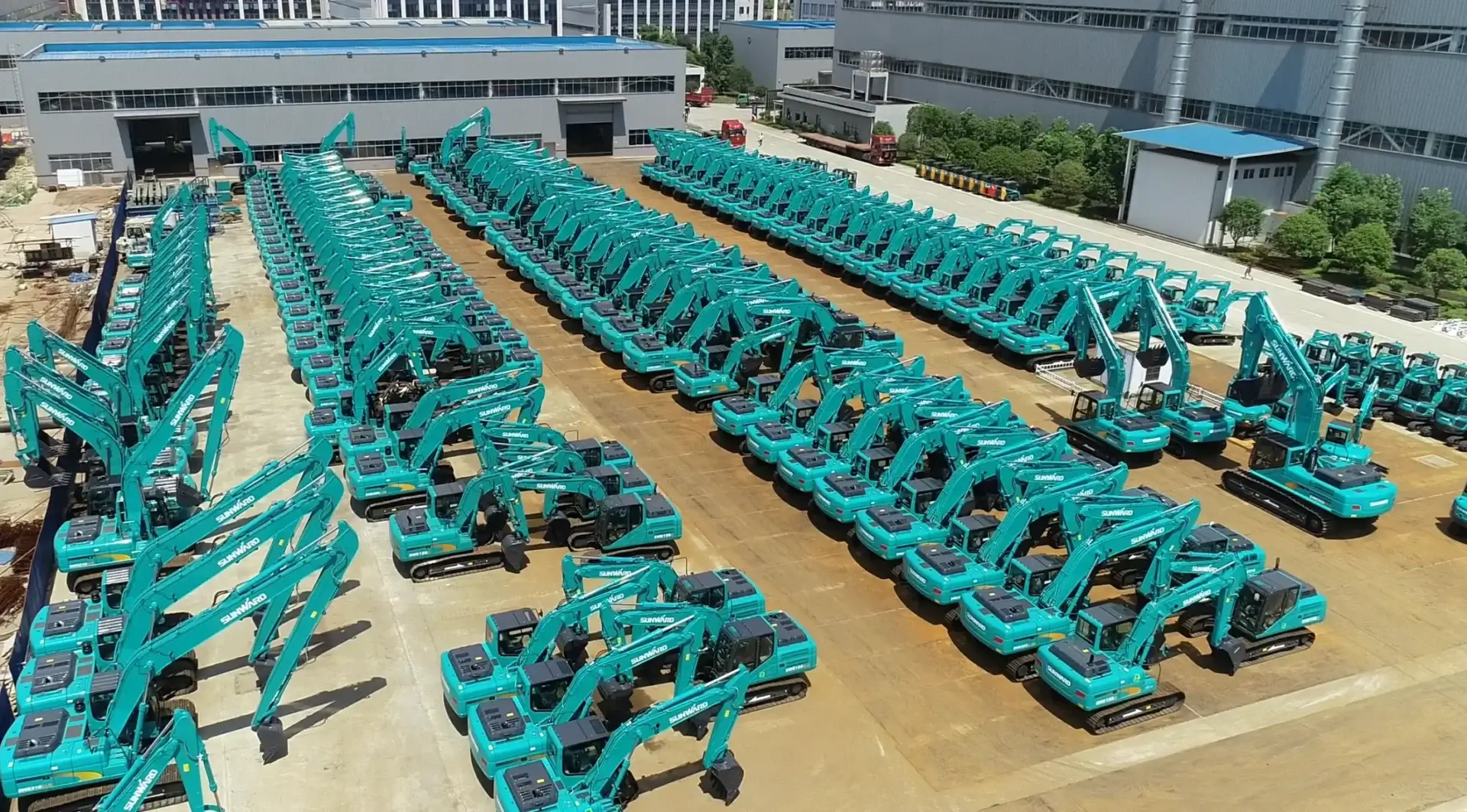 Rows of teal excavators in industrial yard.